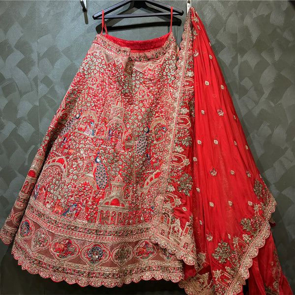 Red embroidered lehenga with intricate panel patterns, silver trim, and matching drape