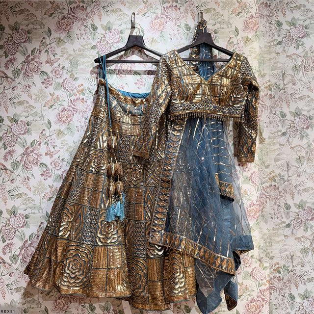 Gold and teal lehenga set on hangers with ornate handwork and sheer dupatta