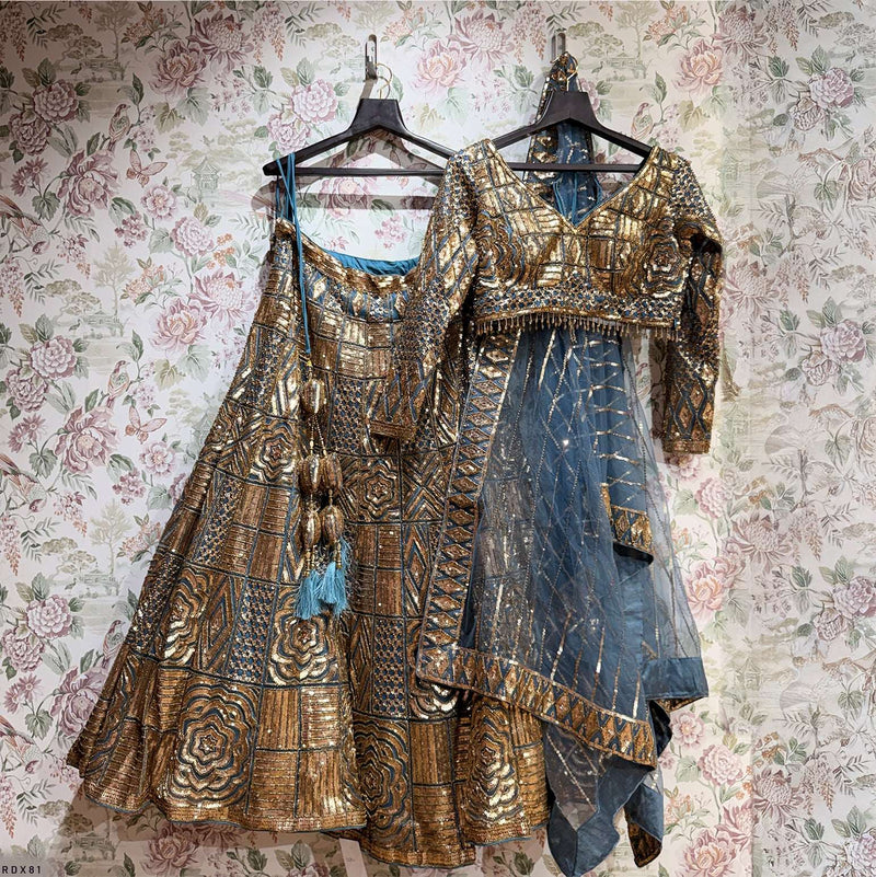 Hanging teal and gold designer lehenga outfit with sequined blouse and draped dupatta