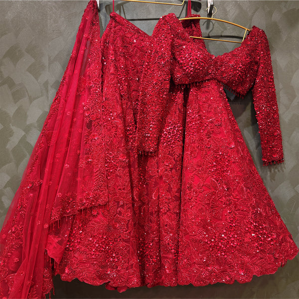 Red sequined bridal lehenga dress with cropped neckline and layered flare skirt on hanger