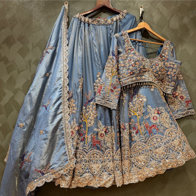 Embroidered blue lehenga with matching full-sleeve blouse and ornate border on hangers