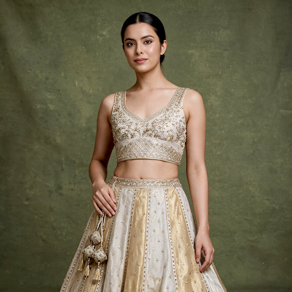 Offwhite lehenga top and skirt with gold embroidered V-neck sleeveless blouse and belt