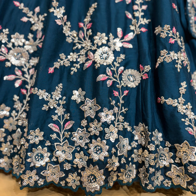 Close-up of blue lehenga fabric with silver floral embroidery and tiny pink accents