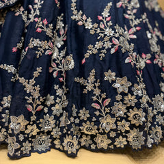 Close-up of navy lehenga fabric with silver zari floral and sequin embroidery border