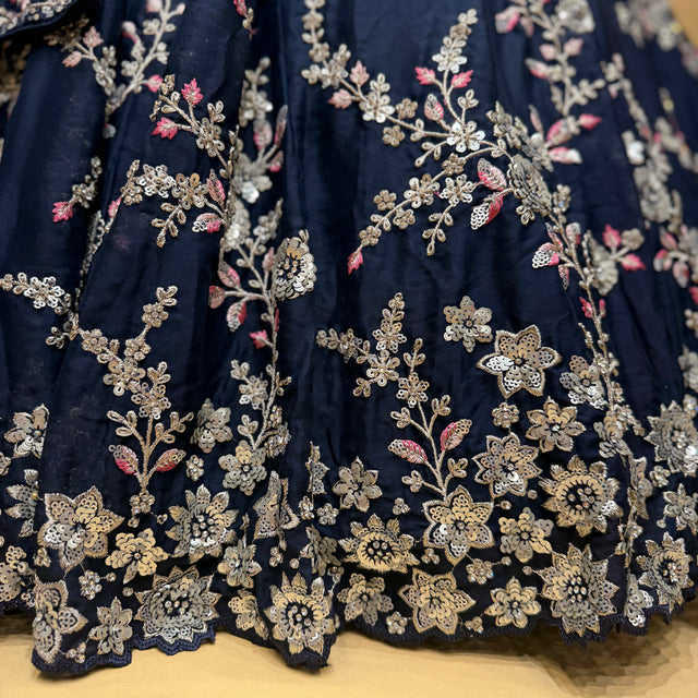 Close-up of navy lehenga fabric with silver zari floral and sequin embroidery border