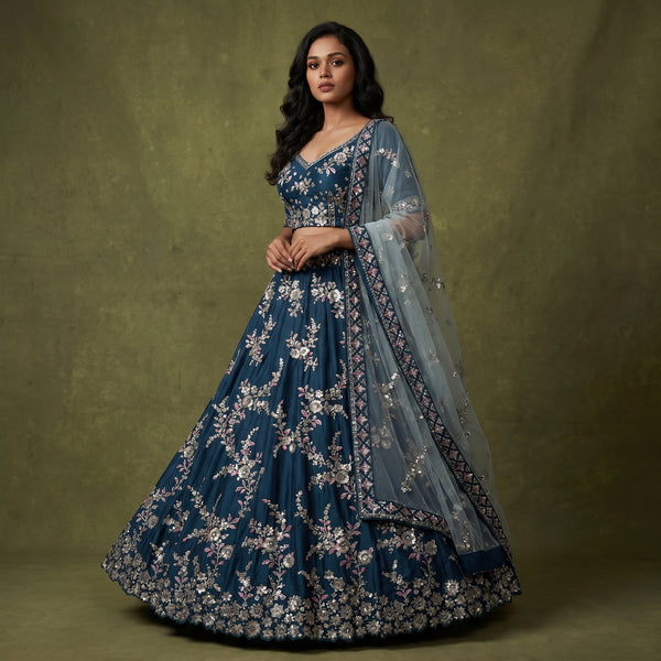 Blue embroidered designer lehenga with silver zari border and floral motifs, plus sheer dupatta