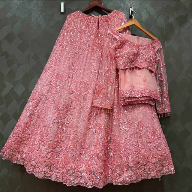 Blush pink reception lehenga with layered blouse and flared skirt, on wooden hangers