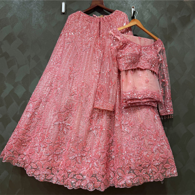 Blush pink reception lehenga with layered blouse and flared skirt, on wooden hangers
