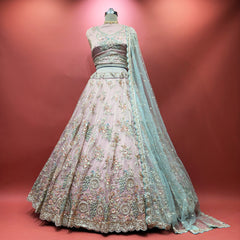 Baby pink lehenga on mannequin with multicolor floral embroidery and sheer teal dupatta