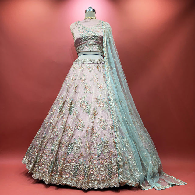 Baby pink lehenga on mannequin with multicolor floral embroidery and sheer teal dupatta