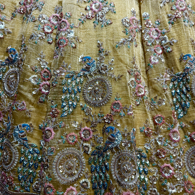 Close-up of yellow embroidered fabric with blue, pink, and silver sequins and beadwork