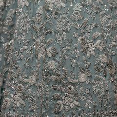 Close-up of sky blue fabric covered in silver beadwork floral vine pattern