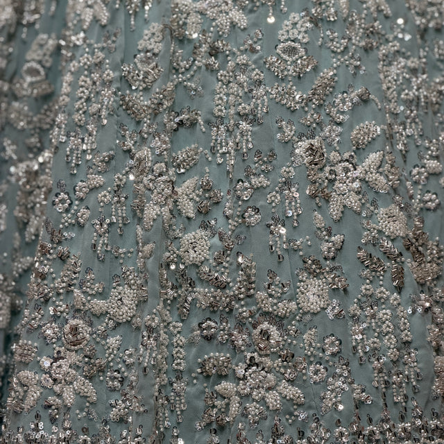 Close-up of sky blue fabric covered in silver beadwork floral vine pattern