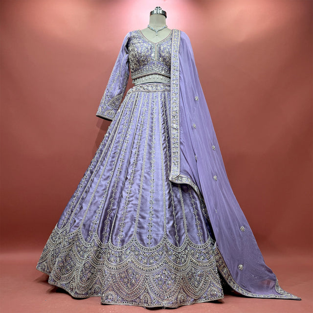 Lavender raw silk lehenga on a mannequin with embroidered floral lines, scalloped hem, full-sleeve blouse and dupatta