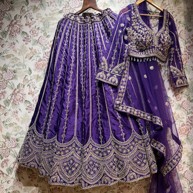 Purple raw silk lehenga with embroidered floral lines and scalloped hem, embroidered blouse and net dupatta on hangers