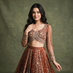 Rust embroidered cropped blouse with long sleeves and detailed neckline over lehenga