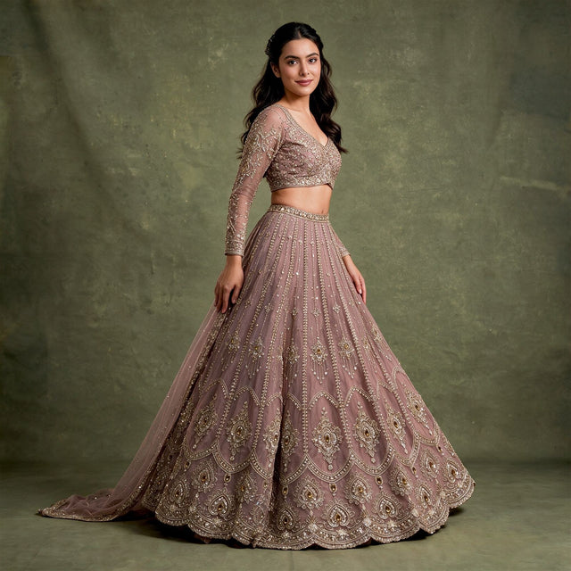 Model in a mauve lilac net lehenga with vertical bead lines, stone-set medallions and a scalloped hem, a full-sleeve V-neck blouse and a net dupatta against an olive backdrop