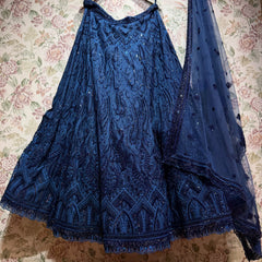 Midnight blue embroidered net lehenga and heavy net dupatta with a scalloped embroidered border, displayed against floral wallpaper