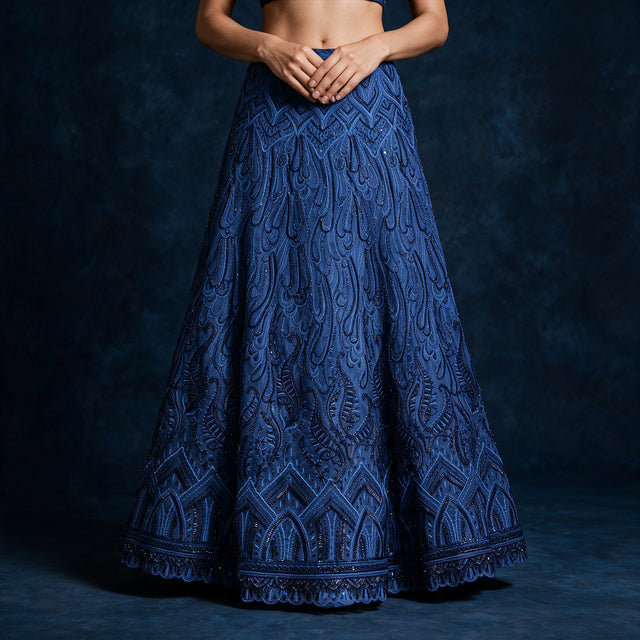 Close-up of the midnight blue net lehenga skirt with layered tone-on-tone paisley and chevron embroidery and a scalloped embroidered hem