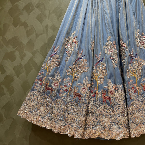 Light blue pleated lehenga skirt with gold trim and multicolor floral embroidery