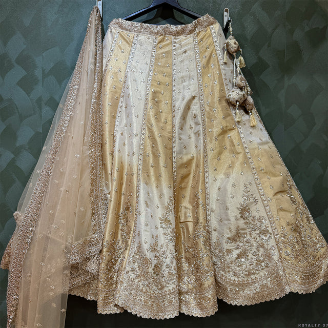 Offwhite and gold lehenga with vertical motif detailing, scalloped hem, and net dupatta