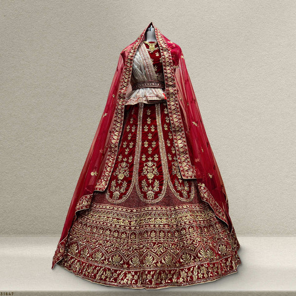 Royal red velvet bridal lehenga with ornate gold embroidery and layered skirt hem detail
