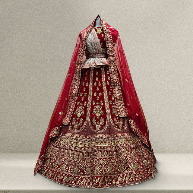 Royal red velvet bridal lehenga with ornate gold embroidery and layered skirt hem detail