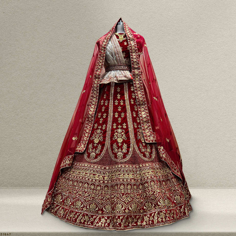 Royal red velvet bridal lehenga with ornate gold embroidery and layered skirt hem detail