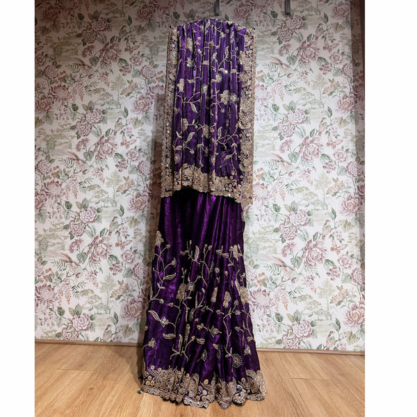 Deep purple crepe saree with gold cutdana work and ornate border, full-length drape.