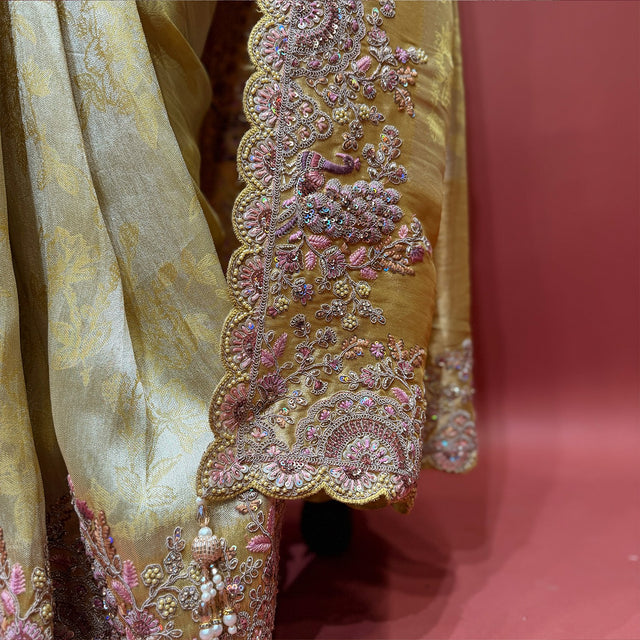 Close-up of pink and mauve resham flower border with zari, stones and tassels on gold Kanjivaram