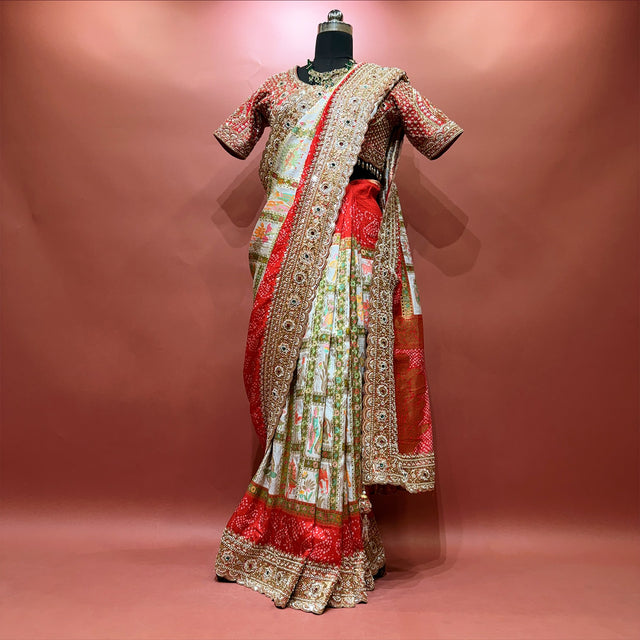 Red gajji silk gharchola saree on a mannequin with the ivory checked body, bandhani red borders, gold handwork border and stitched handwork blouse