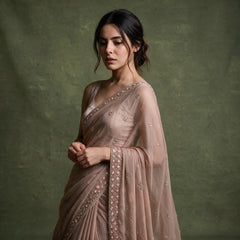 Close-up of the dusty rose chiffon saree draped over the shoulder, showing the cutdana and bead border and scattered small motifs