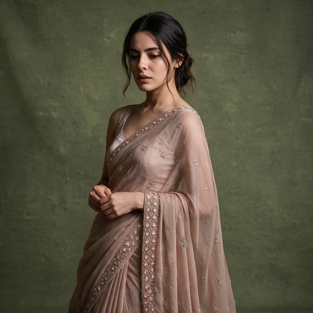 Close-up of the dusty rose chiffon saree draped over the shoulder, showing the cutdana and bead border and scattered small motifs