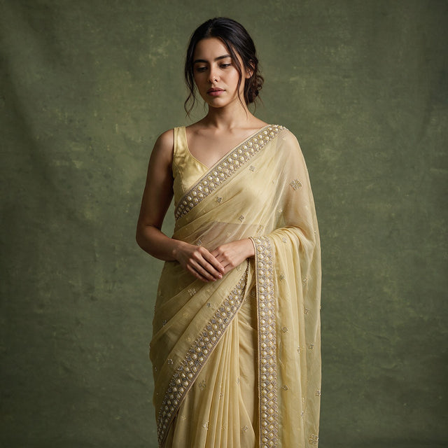 Close-up of the lemon yellow chiffon saree draped over the shoulder, showing the cutdana and bead border and scattered small motifs