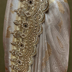 Close-up of pearl bead and handwork border with dark stone centres on woven paisley silk