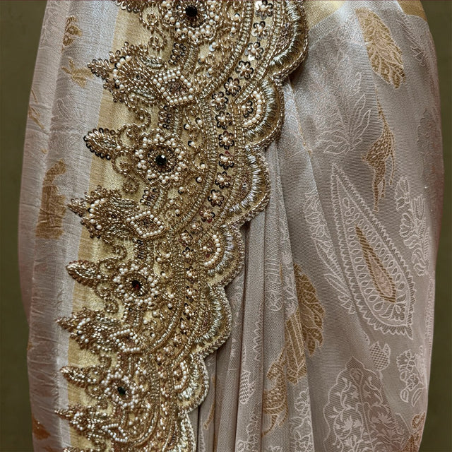 Close-up of pearl bead and handwork border with dark stone centres on woven paisley silk