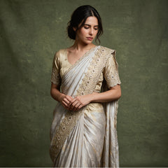 Close-up of the pearl white viscose silk saree draped over the shoulder, showing the scalloped cutdana and bead border with dark stones and the woven paisley pattern