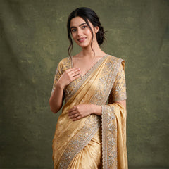 Gold viscose silk saree with leaf-and-vine handwork border draped over the shoulder, worn