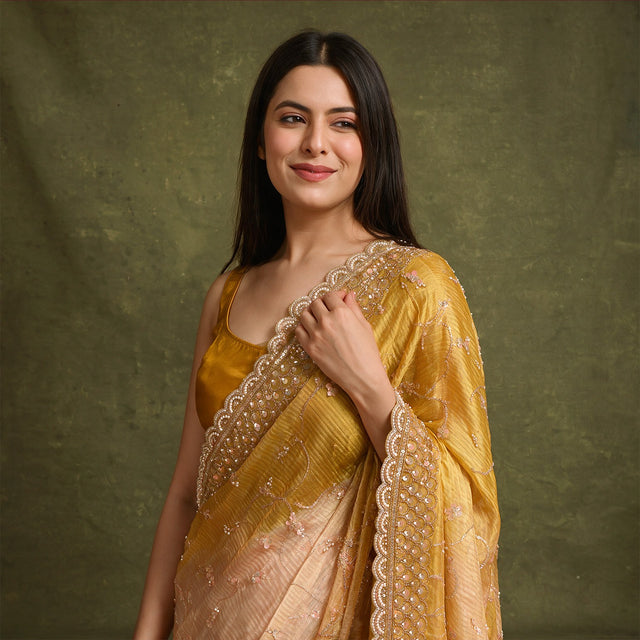 Yellow organza saree with pearl and sequin scalloped border and pink sequin flower jaal work, worn