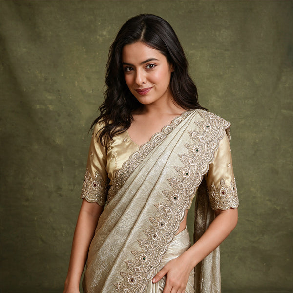 Champagne tissue saree with scalloped leaf and flower handwork border draped over the shoulder, worn