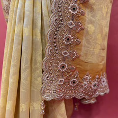 Close-up of rose-gold bead and cutdana flower border with dark stone centres and tassels on pale yellow silk