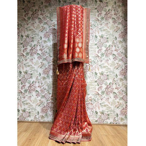 Red georgette saree with bandhani-style pattern and mirrorwork border, draped pallu