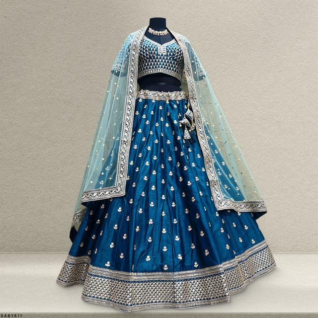Blue lehenga with gold buti and silver hem border; light aqua net dupatta with lace edge.