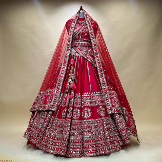 Red bridal lehenga with ornate silver border and patterned ghera skirt, full view