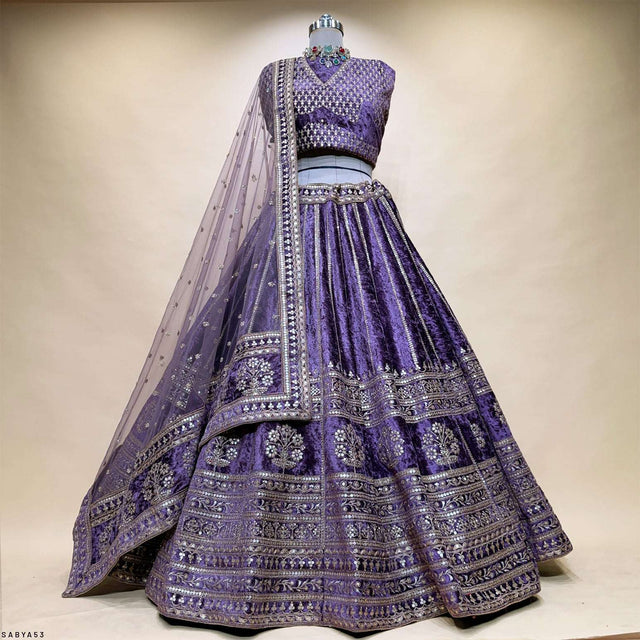 Purple velvet lehenga with flared skirt, ornate gold trim, and embellished veil
