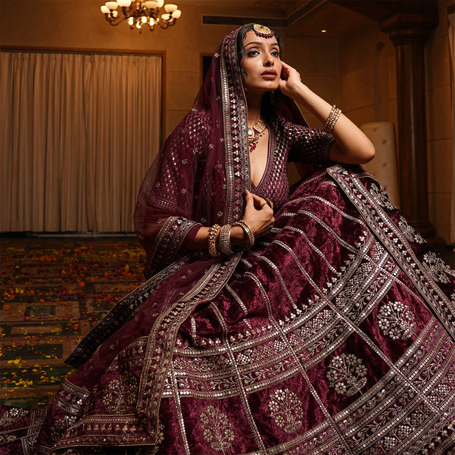 Maroon velvet lehenga with deep V neckline, silver trim, and draped matching dupatta