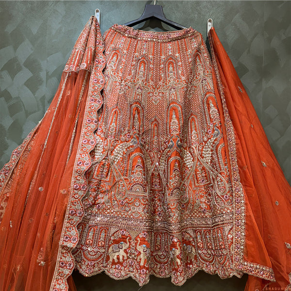 Rust-orange bridal lehenga with dense ornate embroidery and flared skirt, full-length dupatta