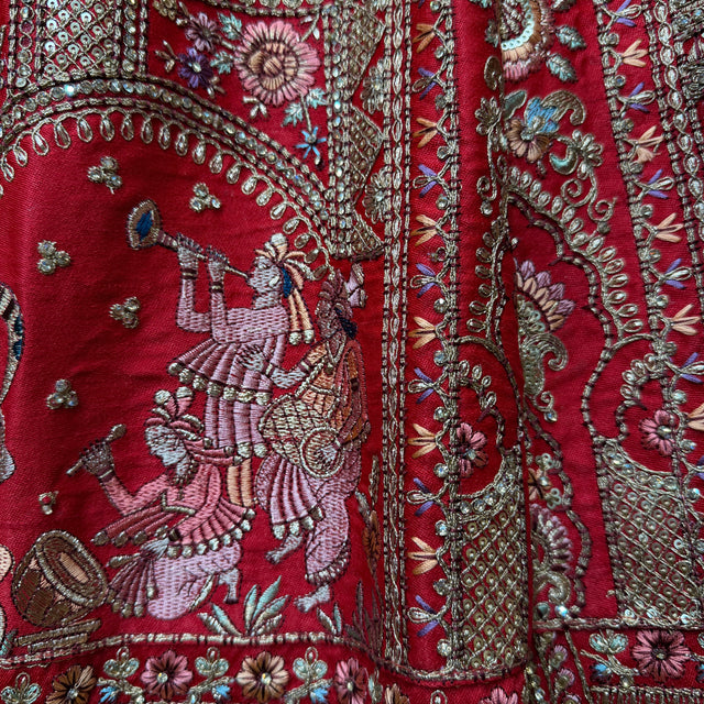 Red bridal lehenga fabric with detailed silver floral and figure embroidery