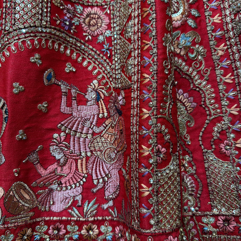 Red bridal lehenga fabric with detailed silver floral and figure embroidery
