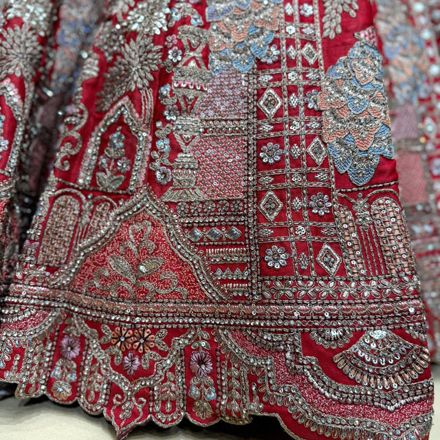 Red bridal lehenga fabric detail with dense silver embroidery and border trim